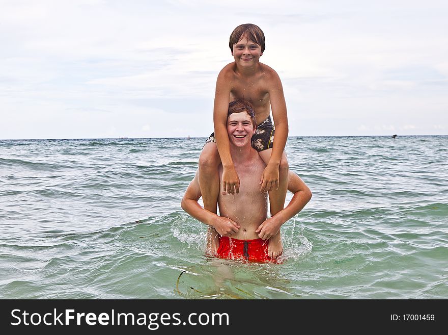Boys having fun in the beautiful clear sea by playing pickaback