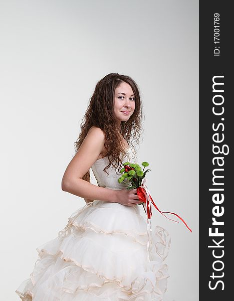 Smiling bride in wedding dress with bouquet. Studio shot