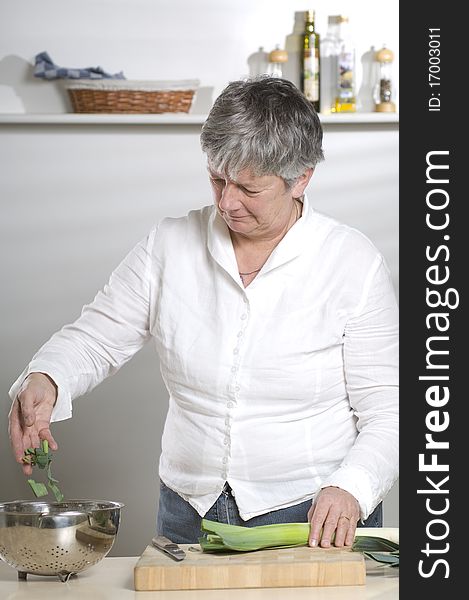 Women is cutting leek in the kitchen in a bowl