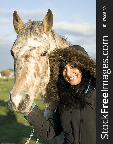 Color portrait photo of a beautiful asian woman smiling as she pets an Appaloosa stallion horse. Color portrait photo of a beautiful asian woman smiling as she pets an Appaloosa stallion horse.