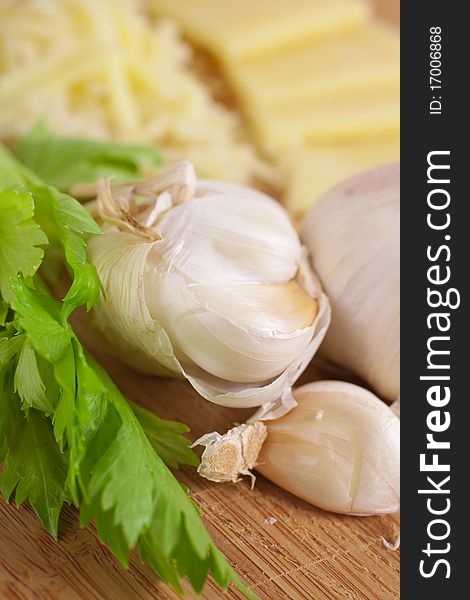 Food ingredients: garlic, cheese and celery on a wooden board