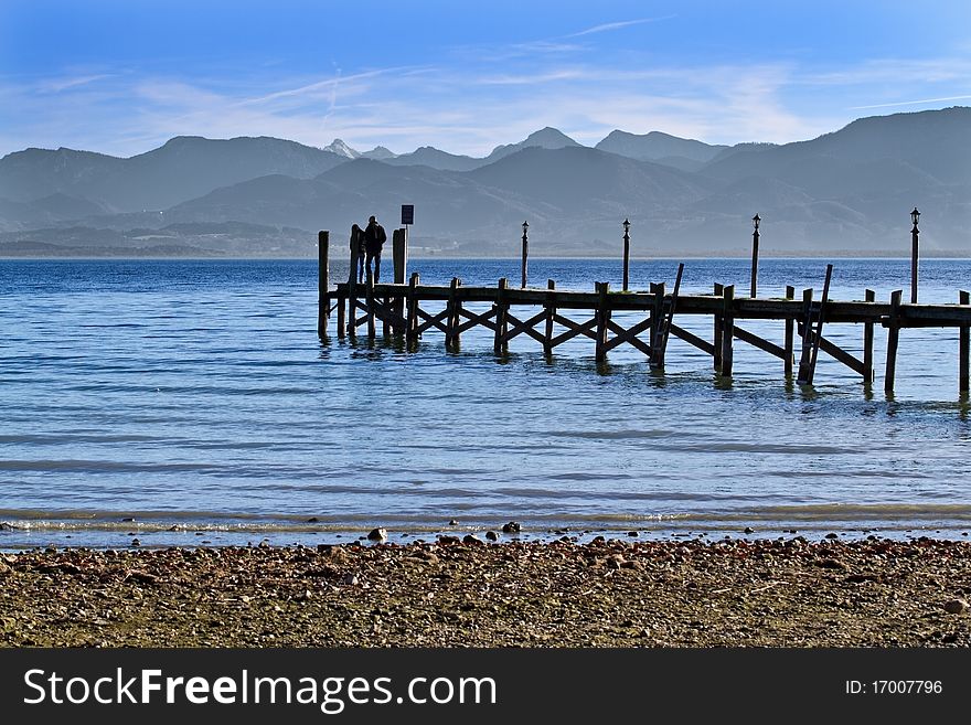 Couple standing on a jetty at lake Chiemsee in autumn