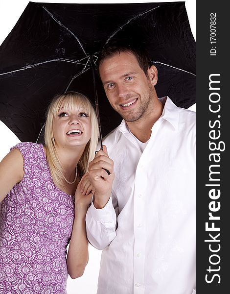 A happy couple hiding under an umbrella getting close. A happy couple hiding under an umbrella getting close.