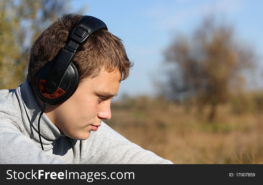 Boy Enjoying Music in headphones in autumn day