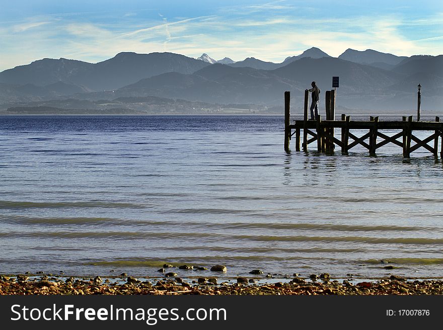 Person standing on a jetty at lake Chiemsee in autumn