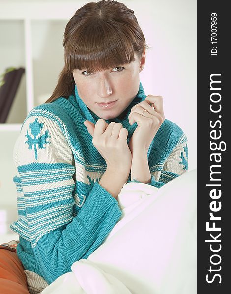 Young woman in knit sweater sitting on sofa at home. Young woman in knit sweater sitting on sofa at home