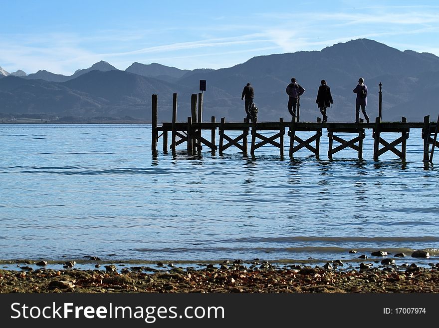 People standing on a jetty at lake Chiemsee in autumn