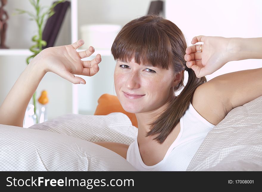 Young woman waking up and stretching on bed