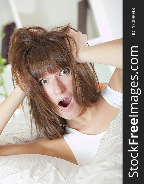 Bed clock alarm - surprised woman in bed holding her head with both hands