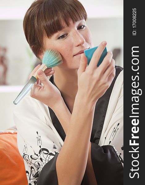 Young woman in bathrobe holding make up brush. Young woman in bathrobe holding make up brush