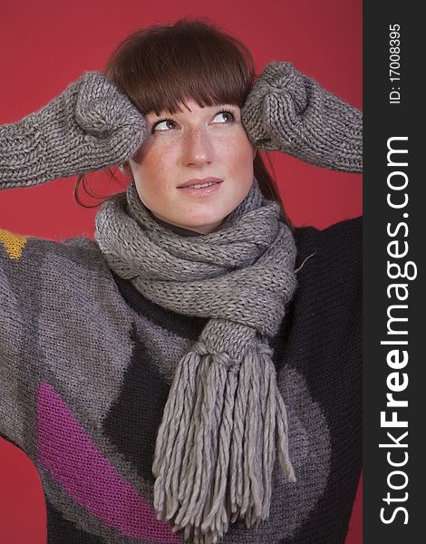 Casual woman in sweater and gloves over red background