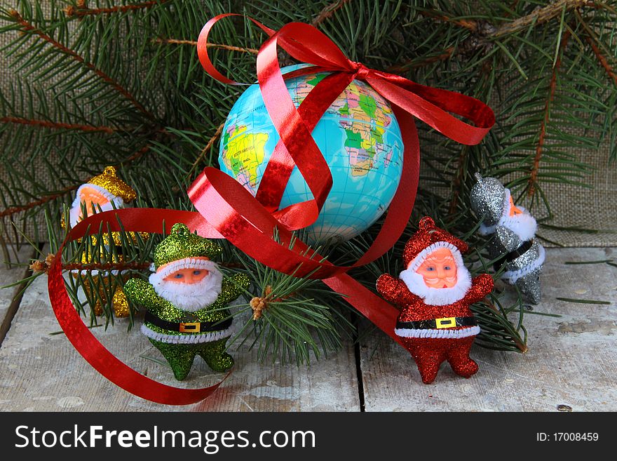 Globe with a gift ribbon and lots of Santa Clauses around. Globe with a gift ribbon and lots of Santa Clauses around