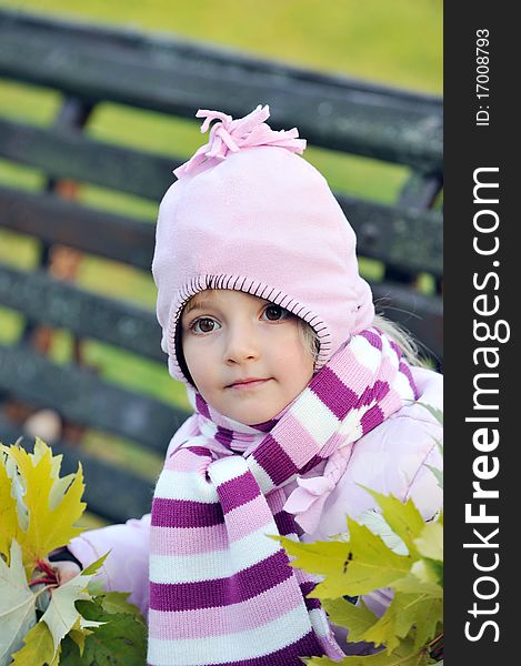 Pretty girl wooden sits on bench in autumn park