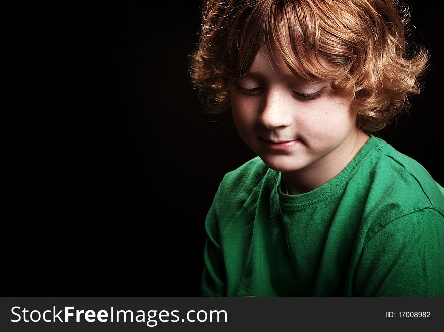 A cute young boy looking thoughtful/pensive on a black background. A cute young boy looking thoughtful/pensive on a black background.