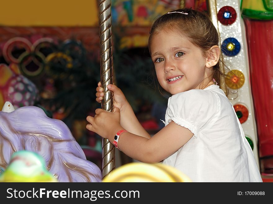 A sweet smiling child is sitting on horse in carousel. A sweet smiling child is sitting on horse in carousel