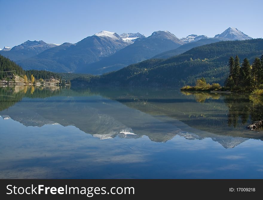 Scenic landscape of the rolling snow-capped mountains with reflection in the lake. Scenic landscape of the rolling snow-capped mountains with reflection in the lake