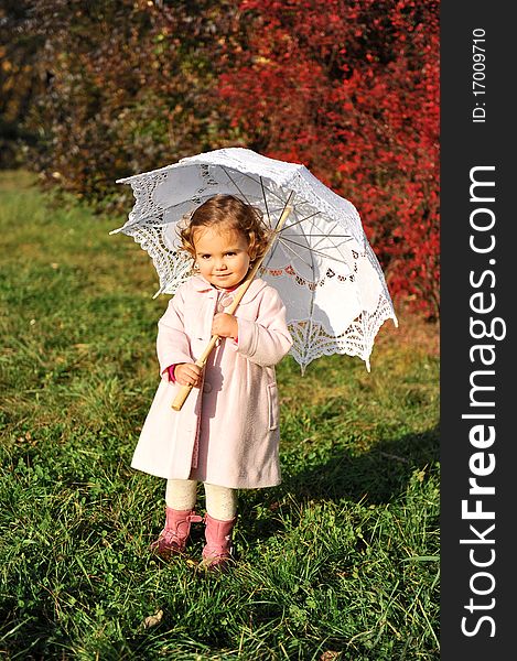 Little girl with umbrella in the park in autumn