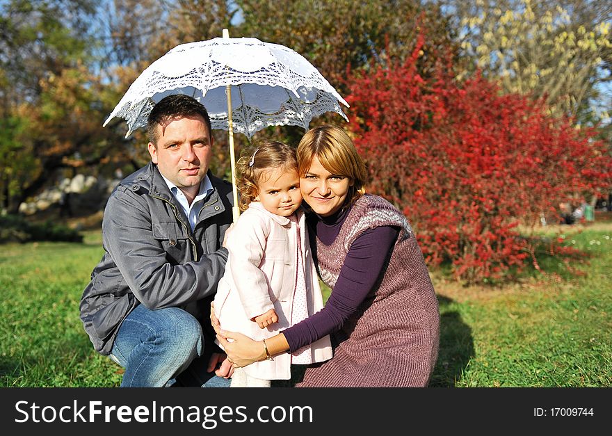 Happy family, mom and dad and their little girl under umbrella. Happy family, mom and dad and their little girl under umbrella