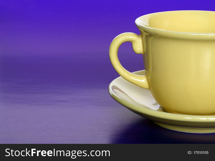 Closeup of empty coffee or tea yellow cup on blue background with copy space. Closeup of empty coffee or tea yellow cup on blue background with copy space