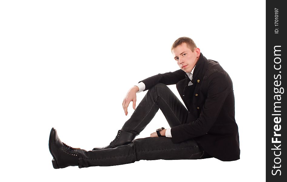 The serious man sitting on a floor against a white background. The serious man sitting on a floor against a white background.