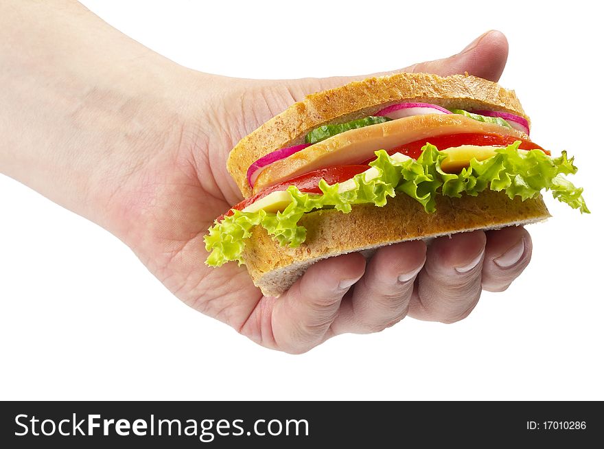 Sandwich with ham, tomato, radish, cucumber and cheese in the hand isolated over white background. Sandwich with ham, tomato, radish, cucumber and cheese in the hand isolated over white background