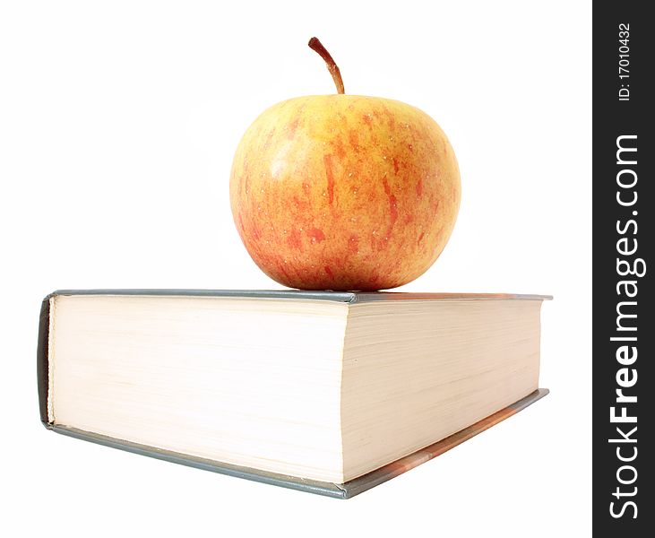 Yellow with red apple lies on corner of closed book. It is isolated on white background, without shadow.