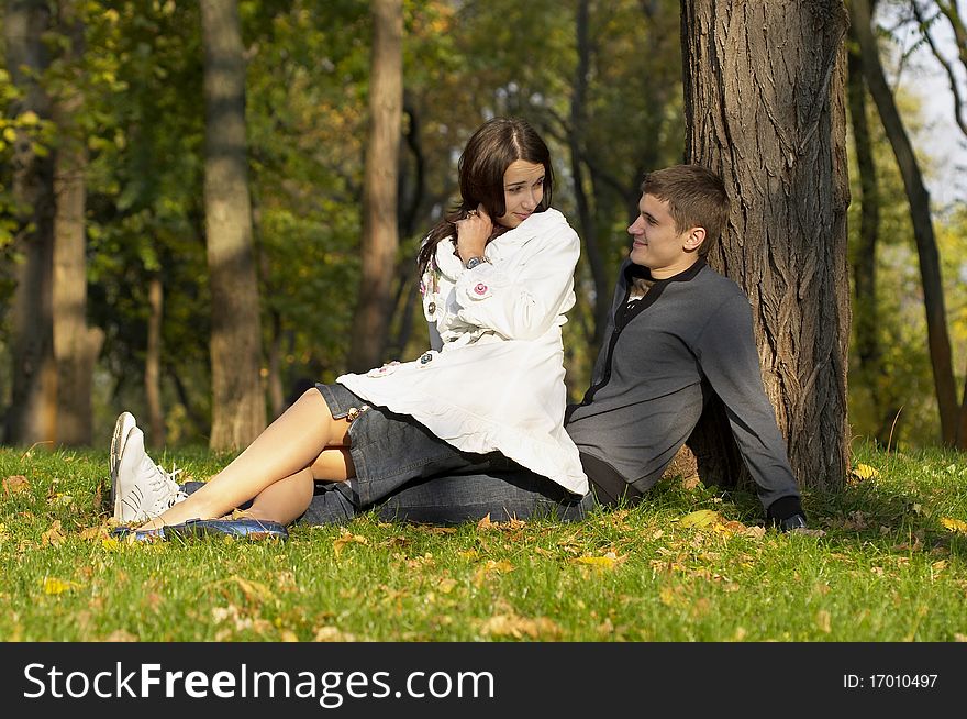 Young couple sitting in the autumn city park (defocused background). Young couple sitting in the autumn city park (defocused background)