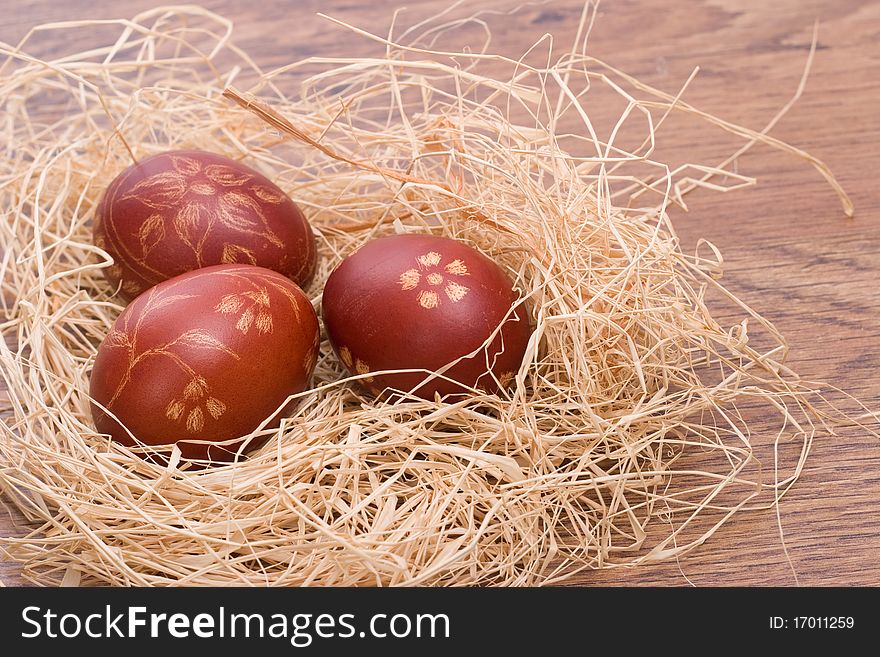 Hand painted red Easter eggs in the hay on a wooden table. Hand painted red Easter eggs in the hay on a wooden table.