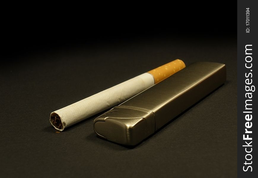 Cigarette and lighter on the dark grey background