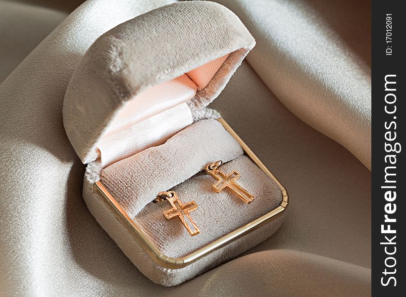 Two golden crosses in a box over beige background. Two golden crosses in a box over beige background.