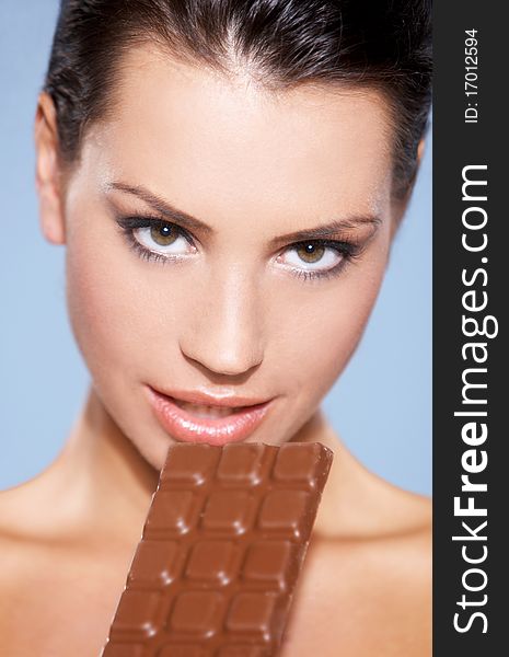 Portrait of beautiful woman, she holding chocolate bar, isolated on blue. Portrait of beautiful woman, she holding chocolate bar, isolated on blue