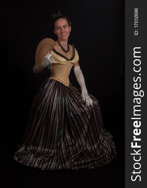 Sitting girl in nineteenth century dress isolated on black