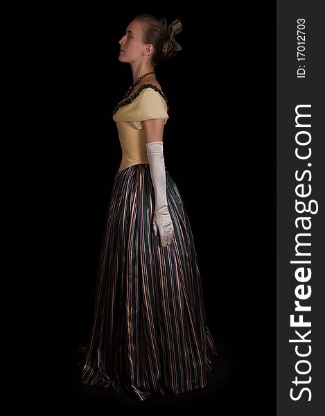 Standing girl in nineteenth century dress isolated on black