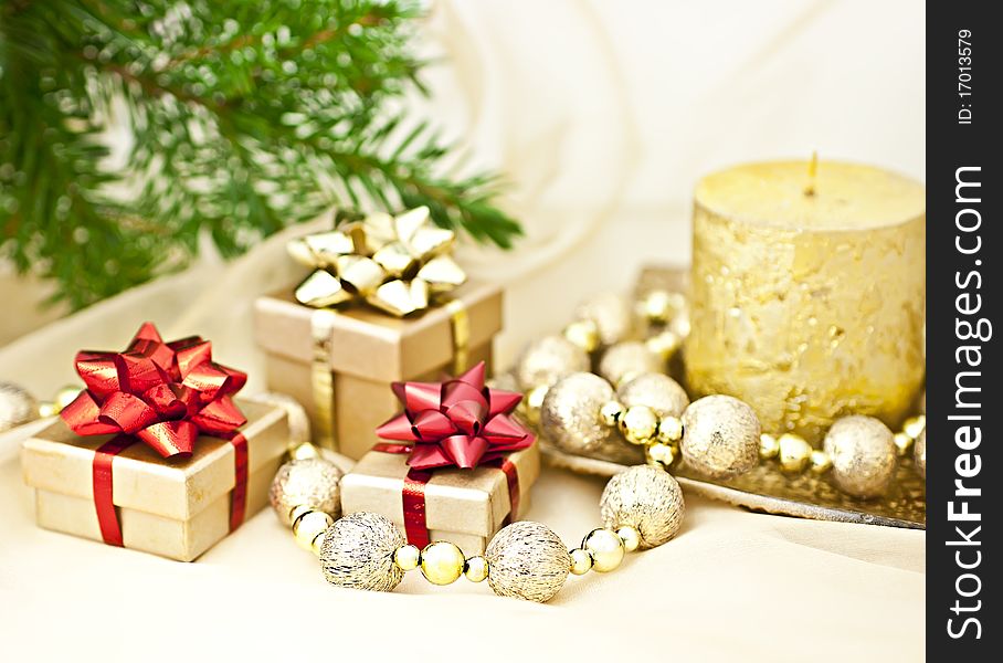 The gold background with a Christmas candle ball chains and gift boxes, a back background fir twig. The gold background with a Christmas candle ball chains and gift boxes, a back background fir twig.