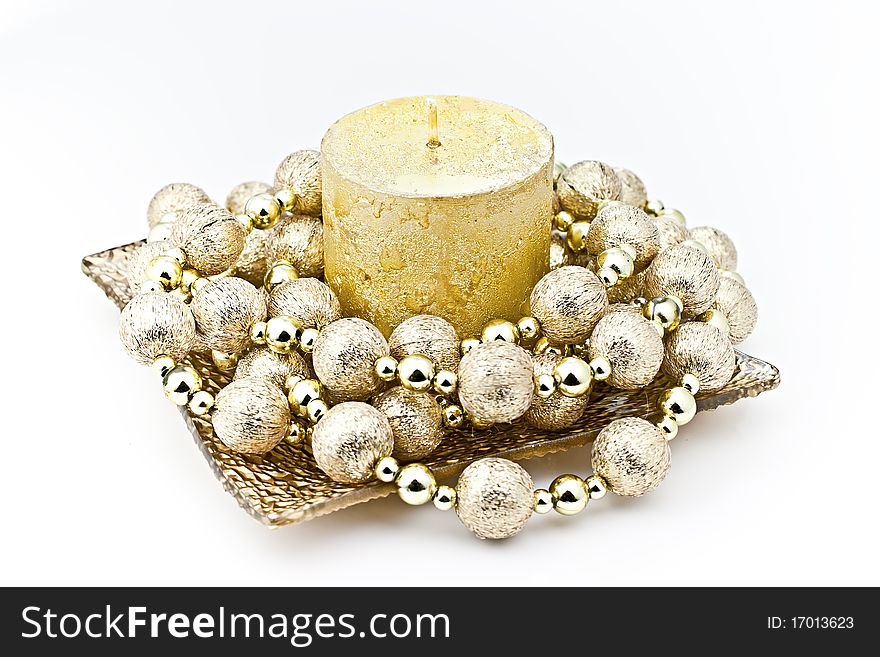 Isolated on white background gold candle in a glass dish with a decorative string of bombs. Isolated on white background gold candle in a glass dish with a decorative string of bombs.