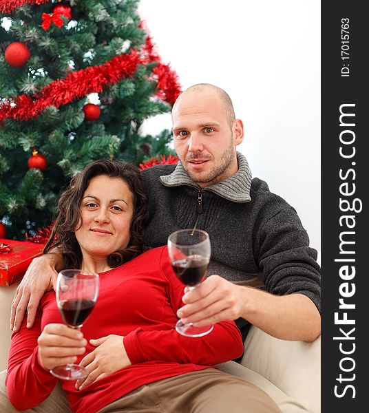 Young couple at sofa celebrating Christmas with a cup of wine. Young couple at sofa celebrating Christmas with a cup of wine