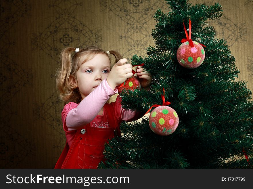 A little girl decorating a new year tree with balls. A little girl decorating a new year tree with balls