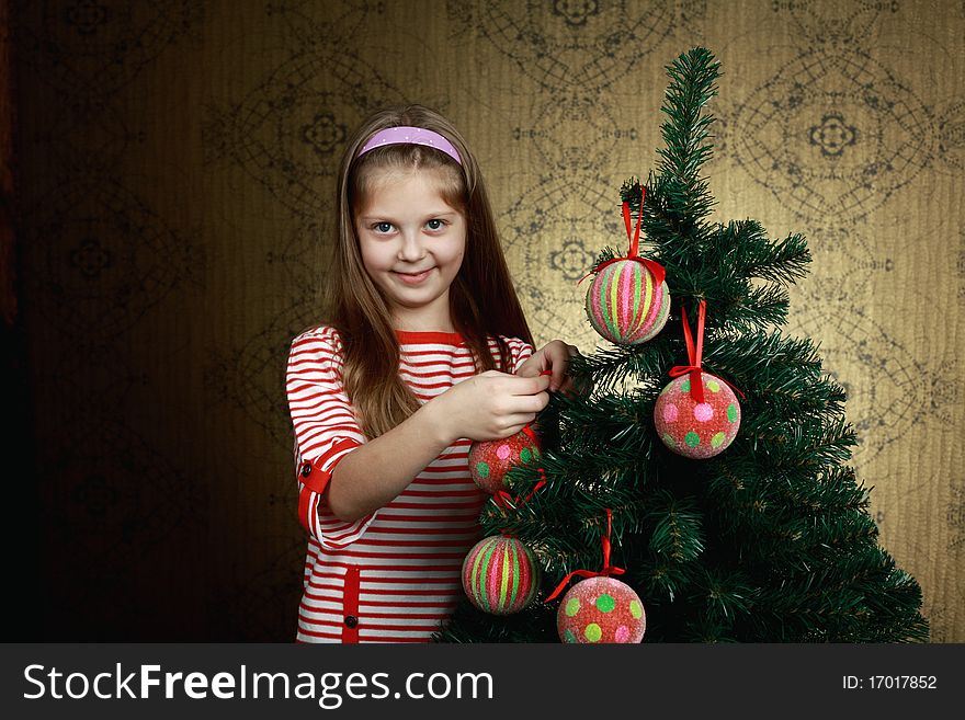 A nice girl decorating a new year tree with balls