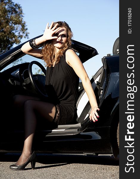 View of a beautiful woman exiting a sports car. View of a beautiful woman exiting a sports car.