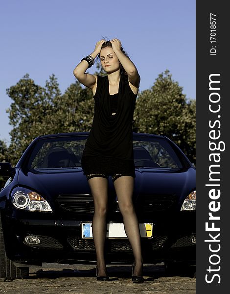 View of a beautiful woman next to sports car on a fashion pose. View of a beautiful woman next to sports car on a fashion pose.