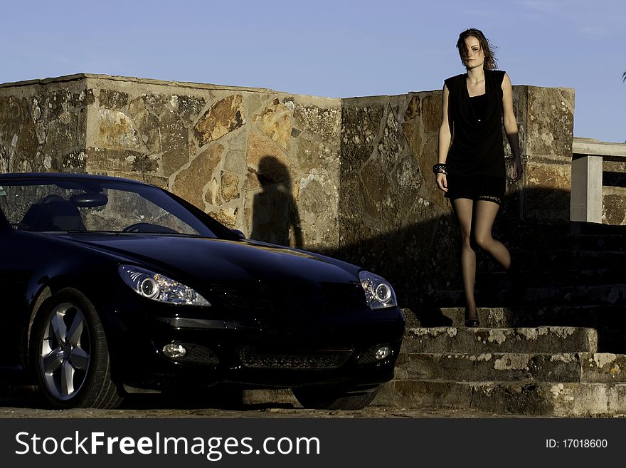 View of a beautiful woman next to sports car on a fashion pose. View of a beautiful woman next to sports car on a fashion pose.