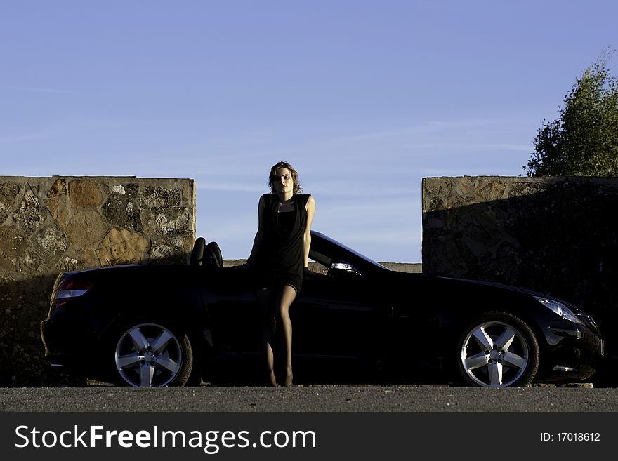 View of a beautiful woman next to sports car on a fashion pose. View of a beautiful woman next to sports car on a fashion pose.