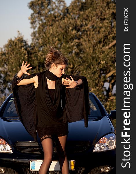 View of a beautiful woman next to sports car on a fashion pose. View of a beautiful woman next to sports car on a fashion pose.