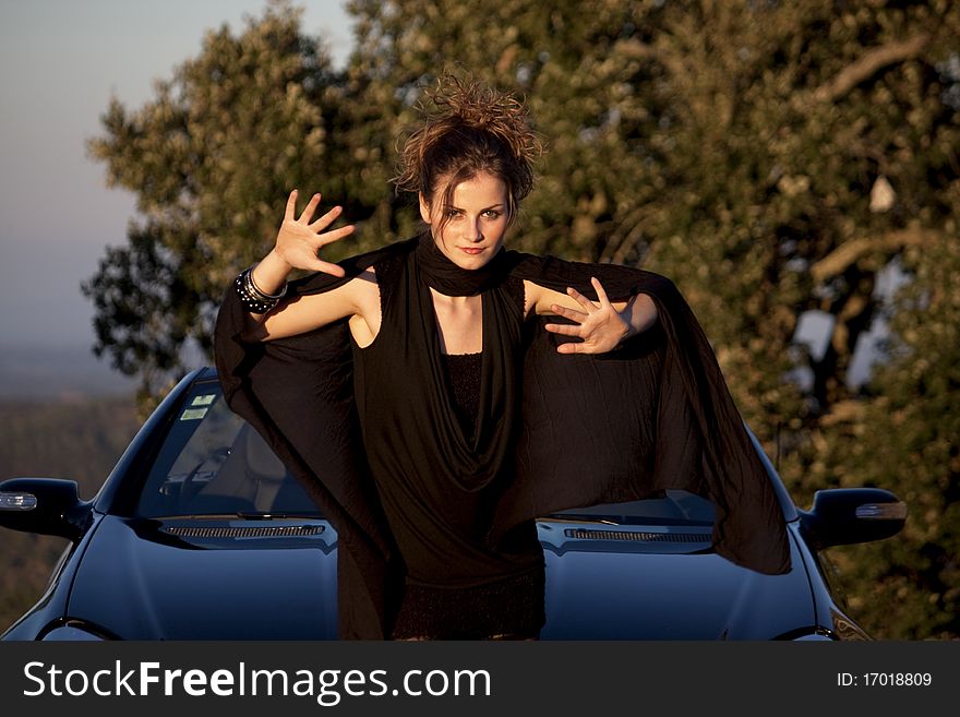 View of a beautiful woman next to sports car on a fashion pose. View of a beautiful woman next to sports car on a fashion pose.