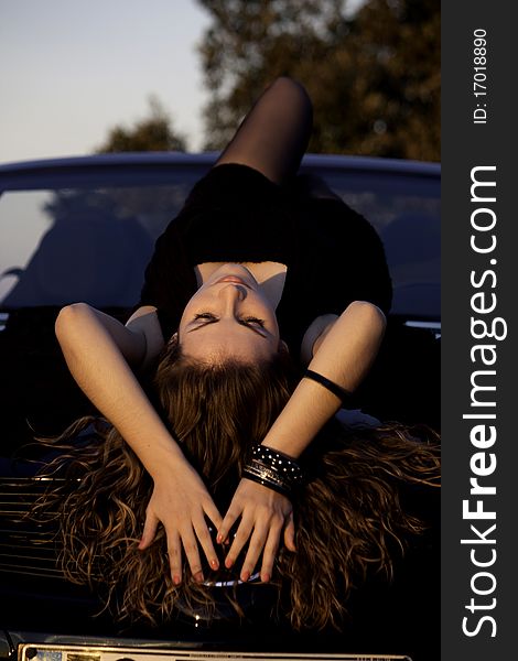 View of a beautiful woman on top of a sports car. View of a beautiful woman on top of a sports car.