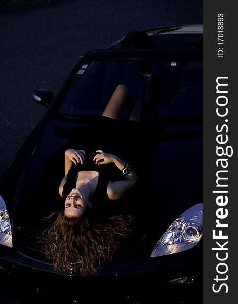 View of a beautiful woman on top of a sports car. View of a beautiful woman on top of a sports car.
