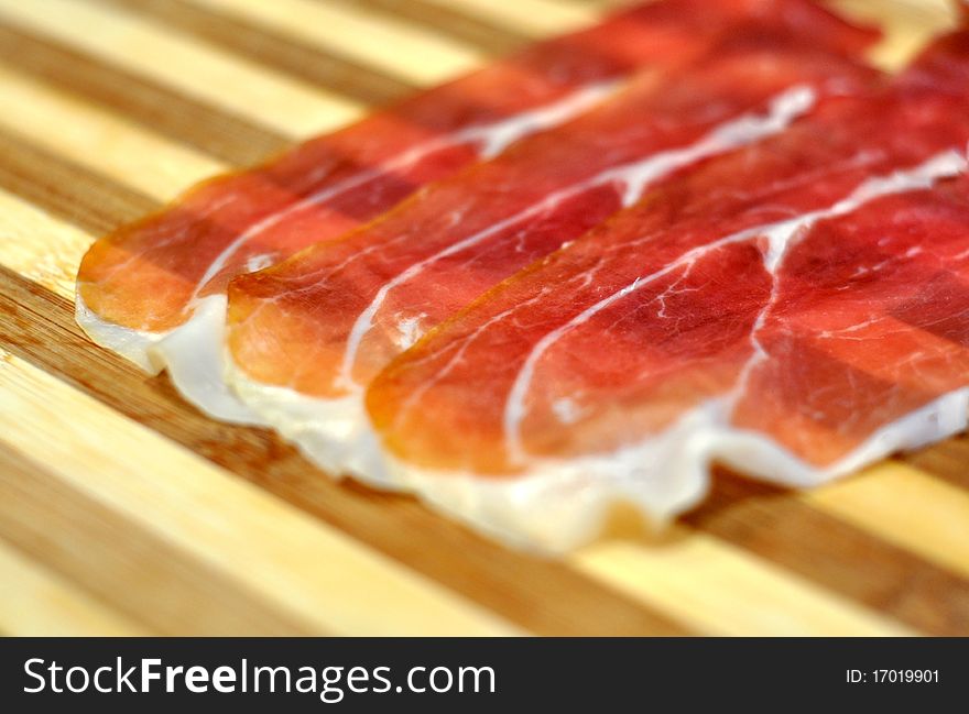 Closeup of cured ham slices over wooden background. Closeup of cured ham slices over wooden background
