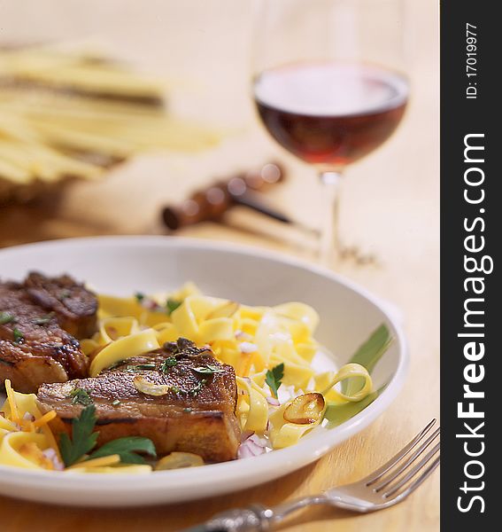 Noddles and meat on white plate together with red wine.