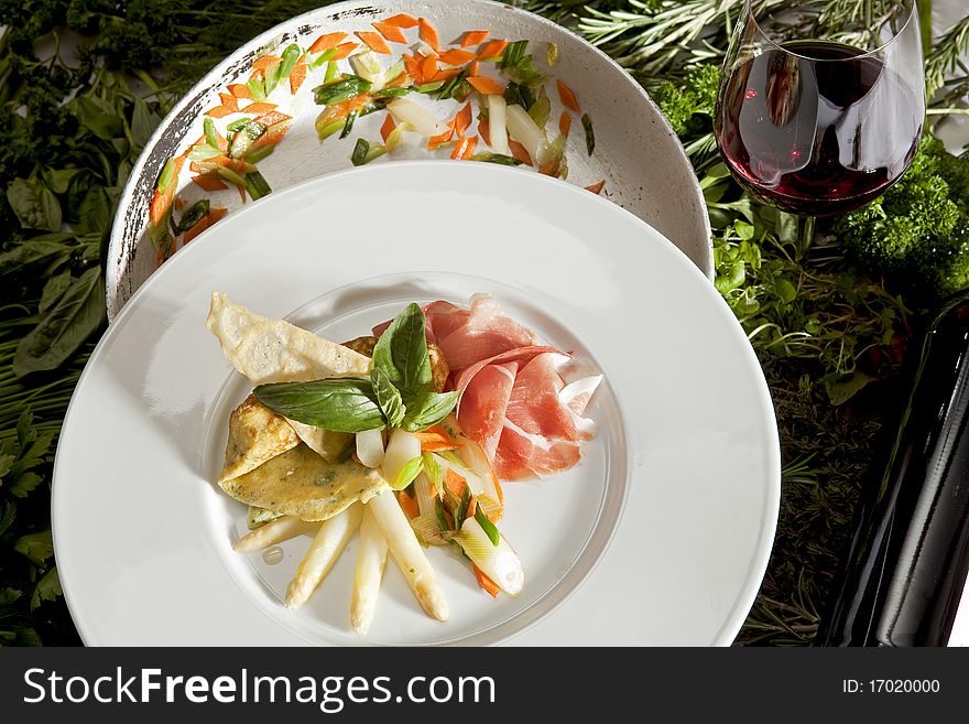 Herb pancakes with asparagus on a white plate with a glass of red wine