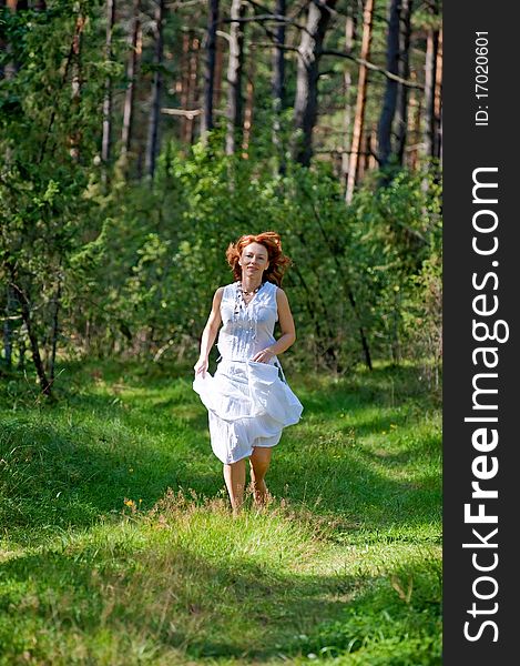 Red-haired woman running on path in the wood. Red-haired woman running on path in the wood